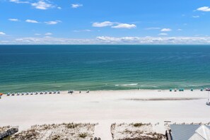 A beach with a clear view of the ocean, a sandy shore, and a few beach umbrellas.