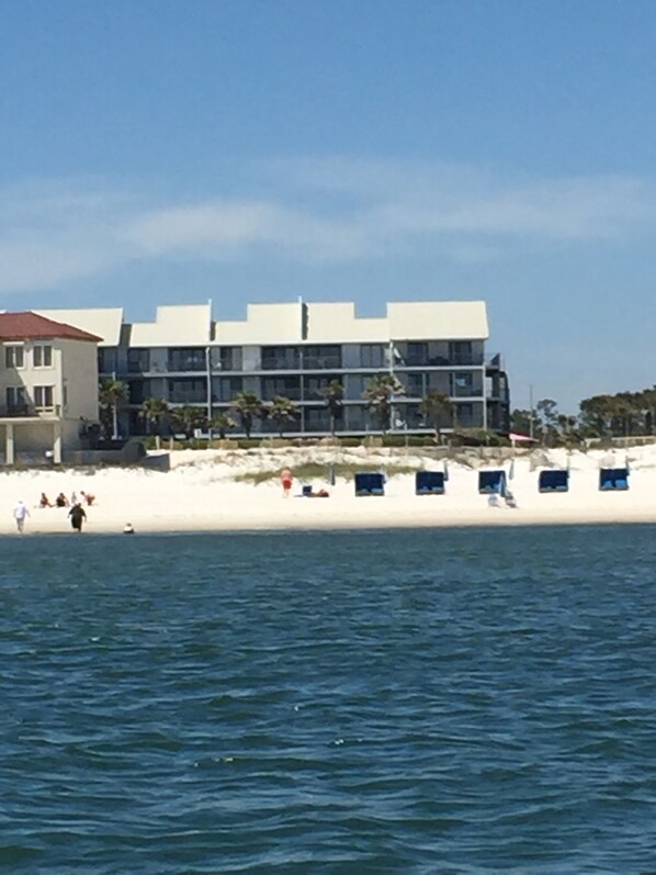 A coastal hotel with a white sandy beach, a pool, and a view of the sea.