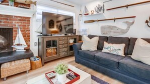 Ein Wohnzimmer mit Kamin, Fernseher, einer Couch und Wanddekoration.
