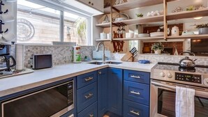 Eine moderne Küche mit blauen Schränken, einem Backofen, einer Mikrowelle und einer Kaffeemaschine.