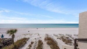 Uitzicht op een strand met een houten hek, een palmboom en een heldere lucht.