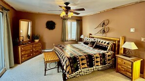 Un dormitorio con cama, cómoda, mesita de noche y ventilador de techo.