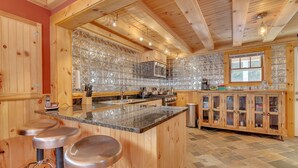A wooden kitchen with a central island, bar stools, and a microwave.
