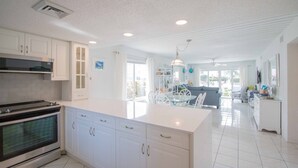 Una cocina moderna con armarios blancos, horno empotrado y una isla grande con encimera blanca.