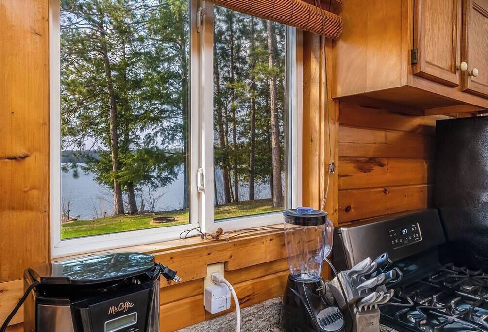 Eine Küche mit Blick auf einen See und Bäume, inklusive Kaffeemaschine, Mixer und Herd.