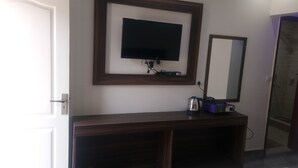 A room with a TV mounted on the wall, a wooden console table, and a mirror.