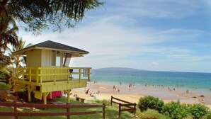 Una torre de salvavidas con vistas a una playa, cielos despejados y aguas tranquilas.
