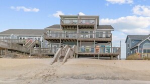 A multi-story beachfront building with a wooden staircase leading to the upper levels.