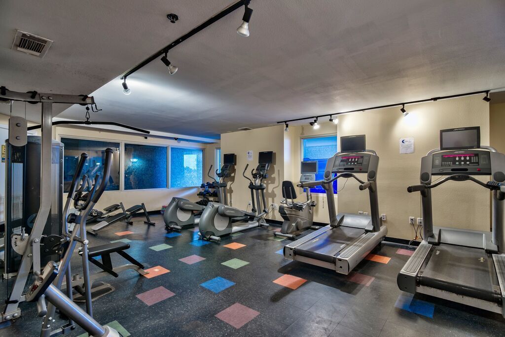 Un gimnasio con cintas de correr, elípticas y equipo de pesas.