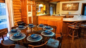 A wooden cabin interior with a dining area featuring a round table set for six with blue plates.