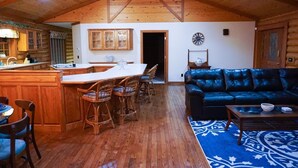 A log cabin interior with a kitchen, dining area, and living room.
