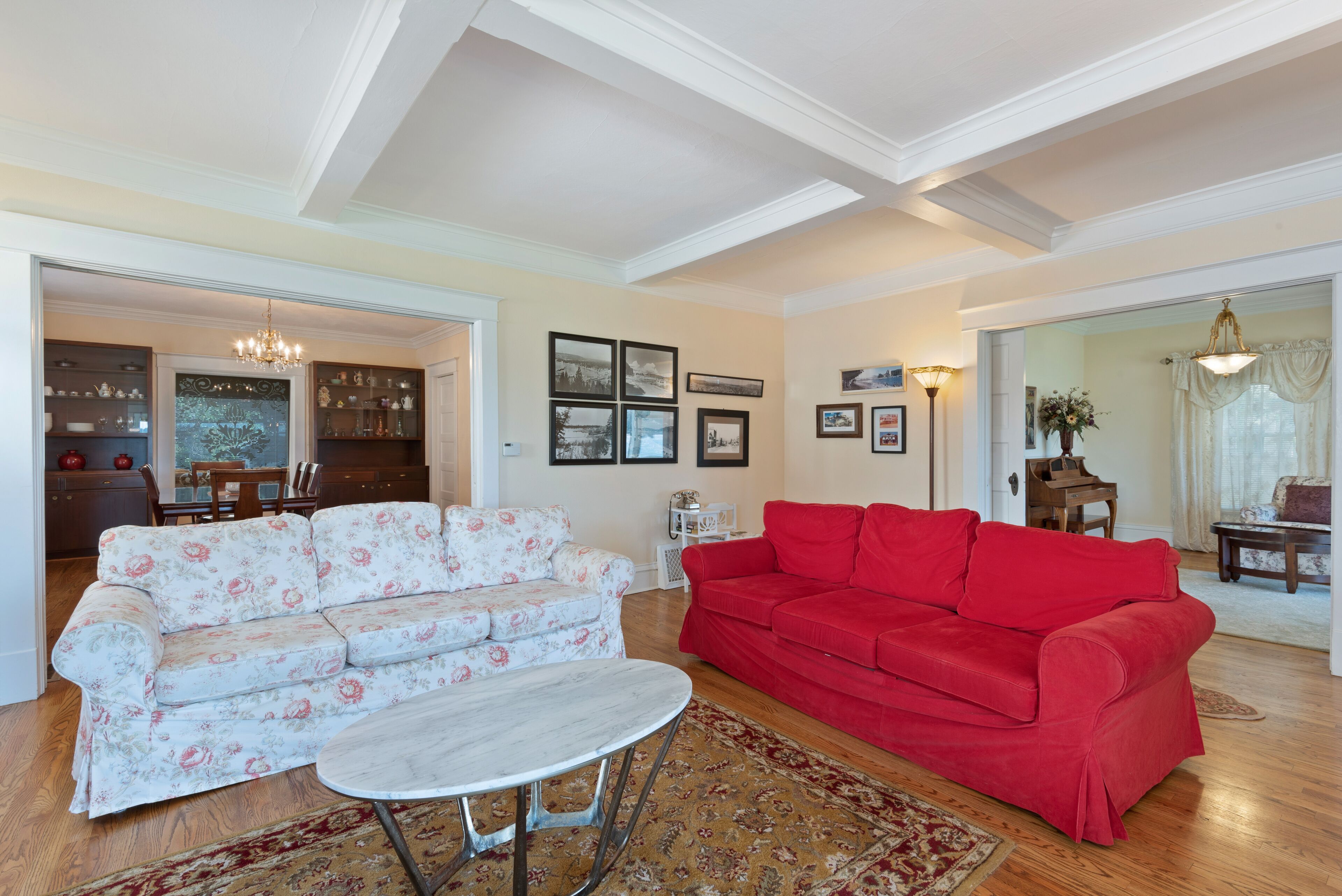 A living room with a floral sofa, a red sofa, and a round coffee table.
