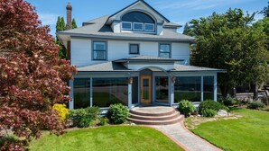 A two-story house with a front porch, a chimney, and a large glass window. - Premiere Beach House, Family Friendly, West Lakeshore Drive (coeur d'alene)