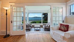 A room with a view of the sea, a white sofa, wicker chairs, and a table. - Premiere Beach House, Family Friendly, West Lakeshore Drive (coeur d'alene)