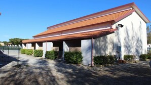 A building with a red-tiled roof, white walls, and a covered entrance area with a gravel driveway. - Camping Blumare Village (Furnari)