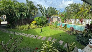 Un jardín cuidado con diversas plantas, un sendero de piedra y una piscina.