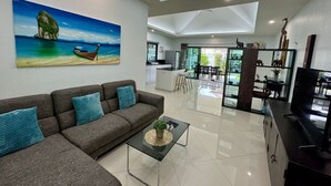 Un salon moderne avec un canapé, une table basse et un tableau représentant un bateau sur une falaise.