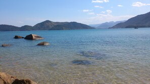 Un lac aux eaux limpides, avec des rochers visibles et des montagnes en arrière-plan.