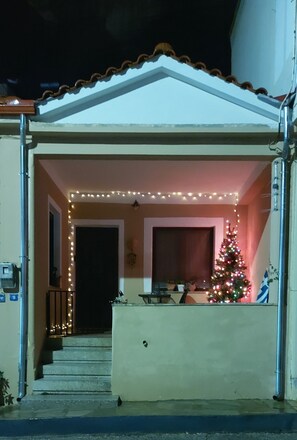 A building with a porch decorated with string lights and a Christmas tree. - Mary's mansion archontiko meteora (Kalabaka)