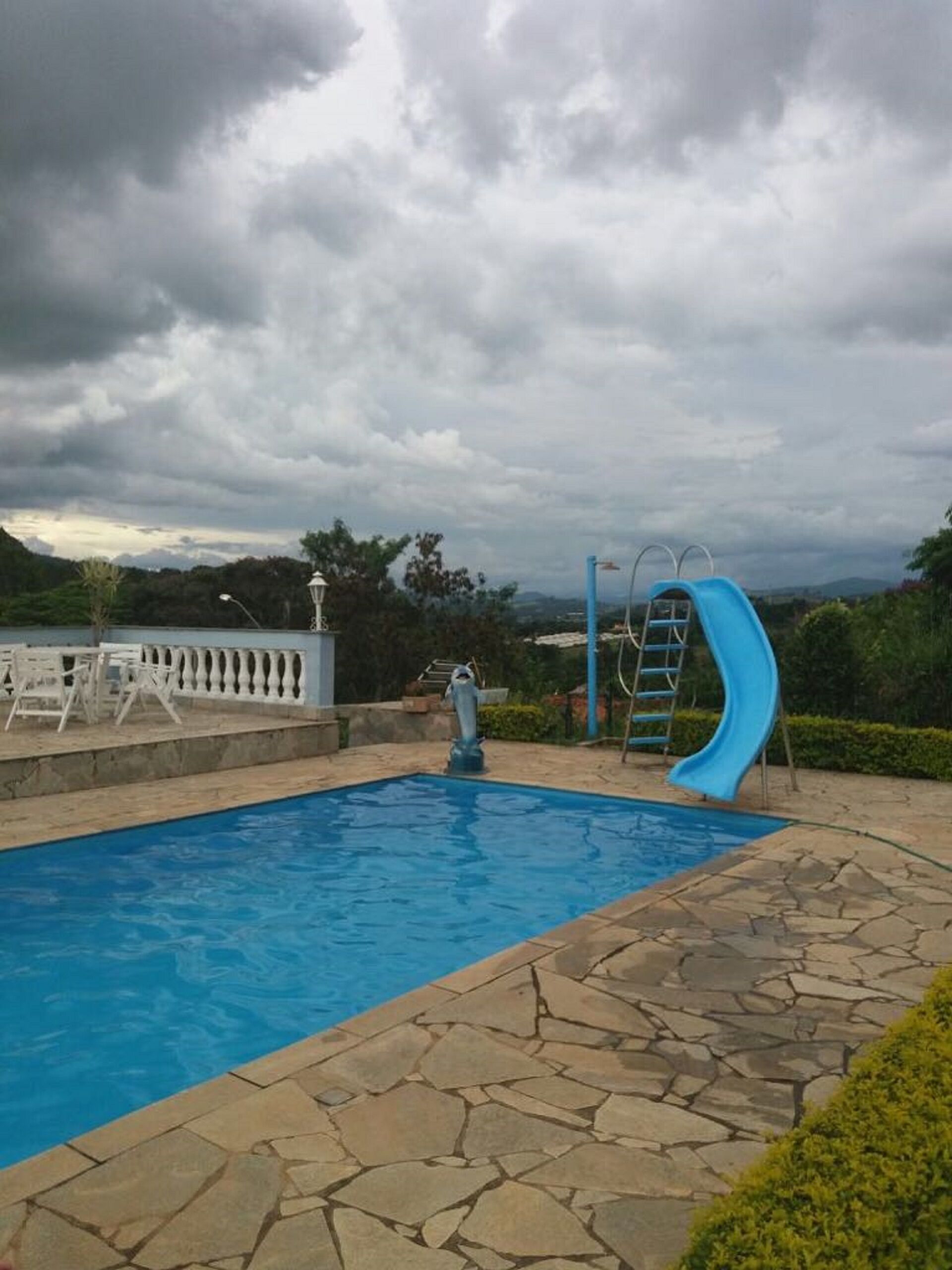 Ein Swimmingpool mit einer blauen Rutsche und einer Delfinstatue.