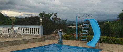 Ein Swimmingpool mit einer blauen Rutsche und einer Delfinstatue.