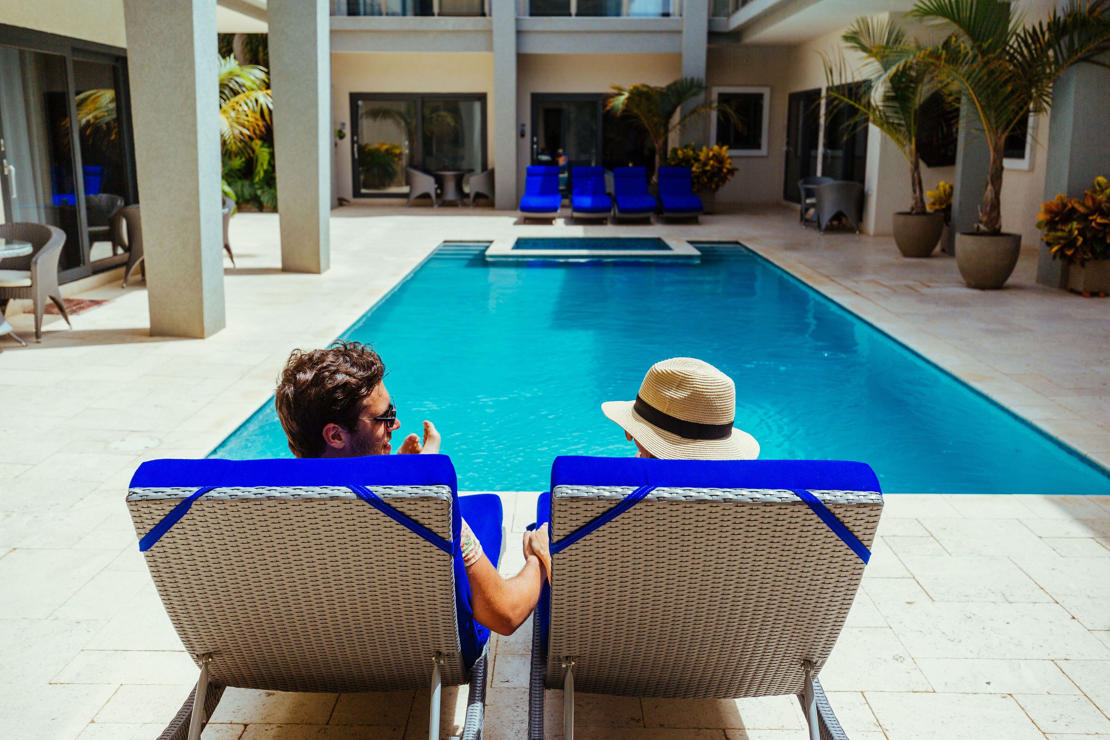 A swimming pool with lounge chairs and potted plants.