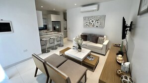 A modern living room with a sofa, coffee table, and a dining area with chairs.