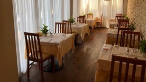 A restaurant with wooden tables and chairs, white tablecloths, and hanging pendant lights. - Hotel Romeo (Torri del Benaco)
