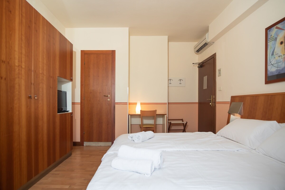 Une chambre d’hôtel avec un lit, une armoire, un bureau et une chaise.