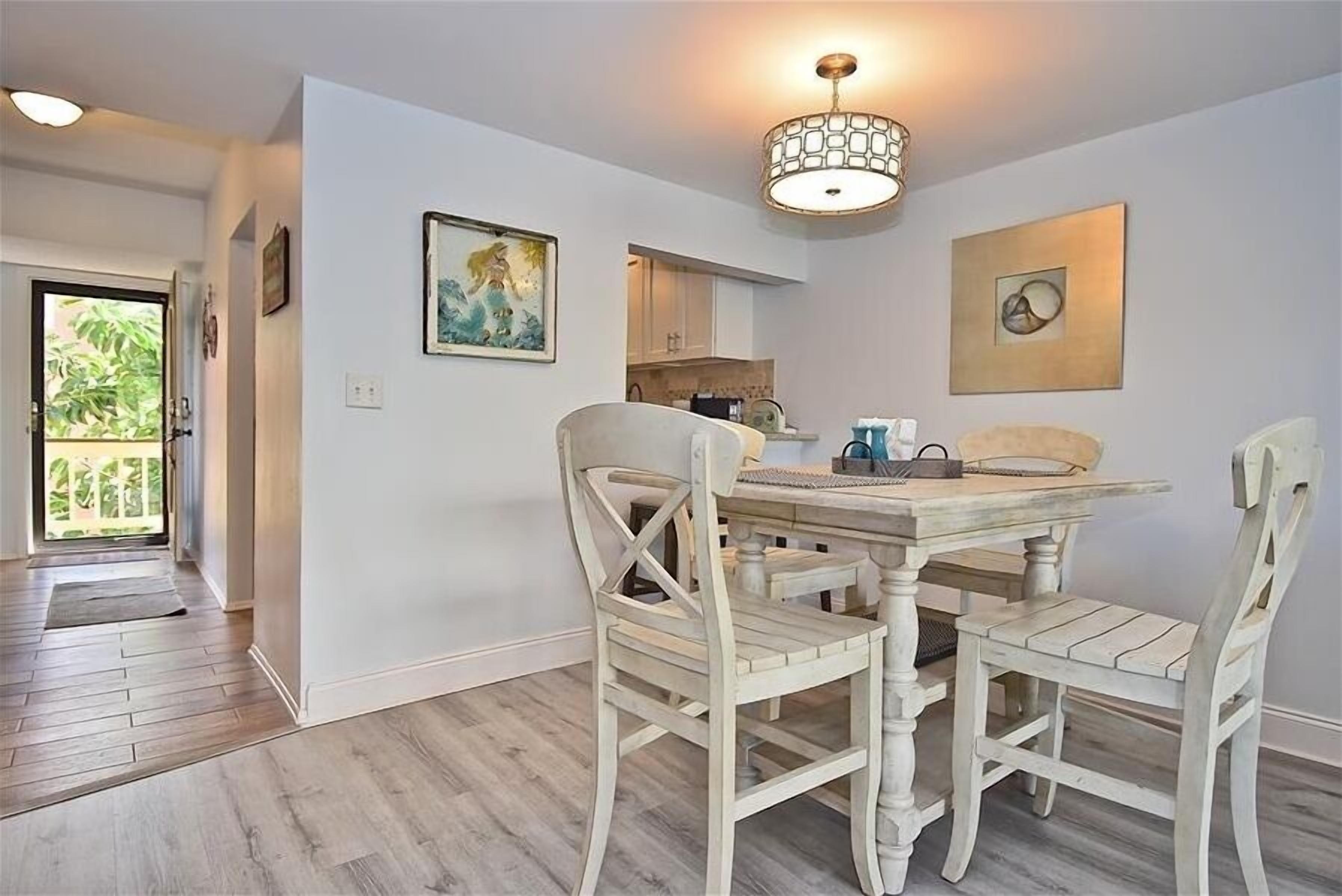 A dining area with a wooden table and chairs, a chandelier, and artwork on the walls.