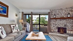 Un salon avec un canapé, une table basse et une cheminée en pierre.
