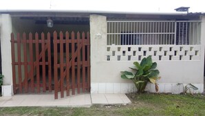 A gated entrance with a red picket fence, a white wall with a window, and a large plant beside the gate. - Beachfront house in Bertioga, 50 meters or 2 minutes from Indaiá Beach. (Bertioga)