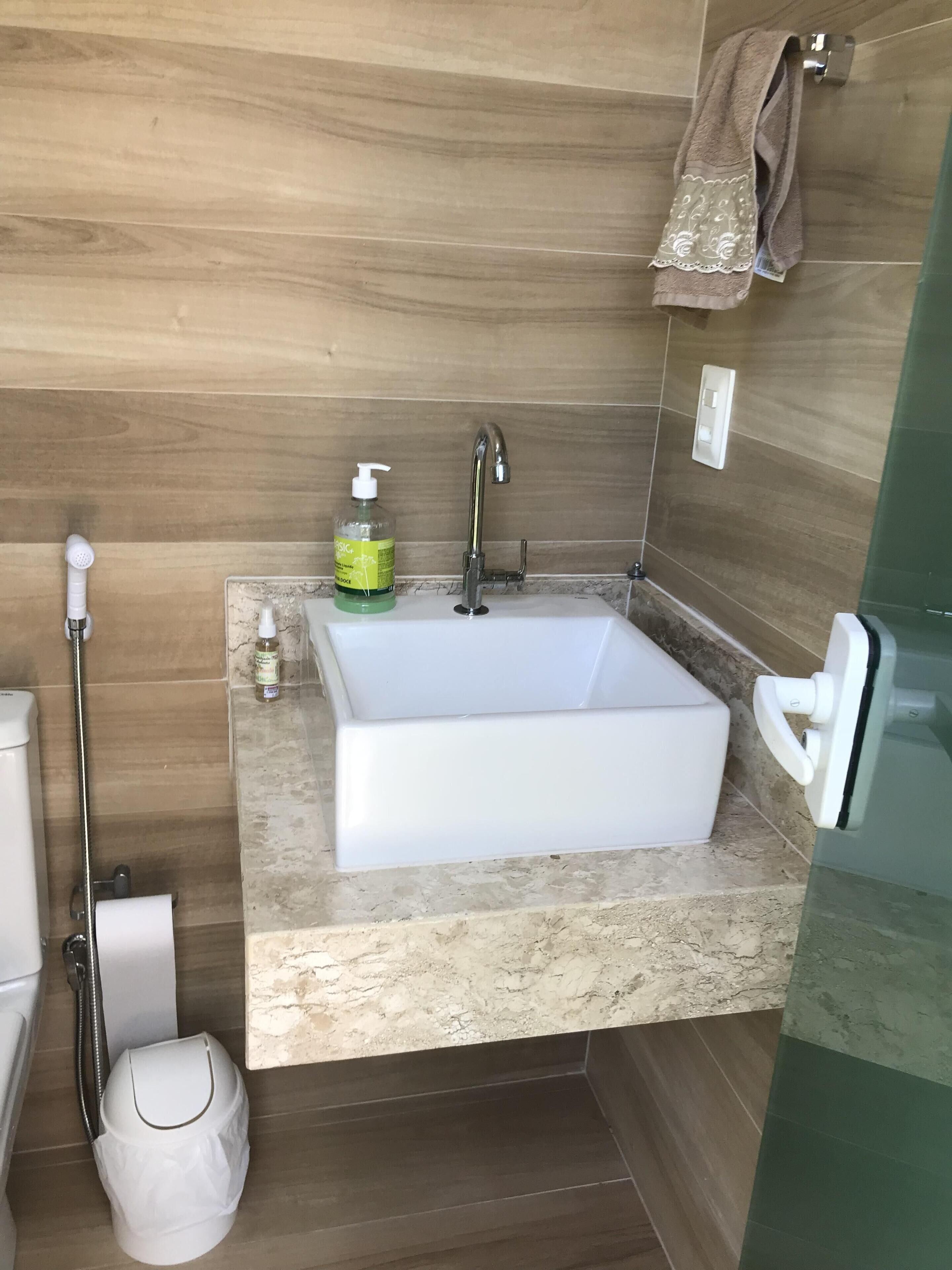 A modern bathroom with a rectangular sink, a handheld showerhead, and a toilet.