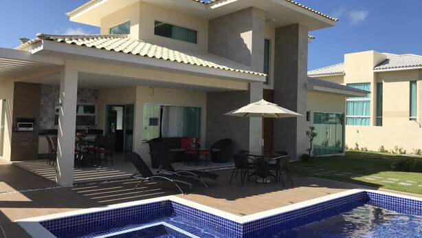 A modern two-story house with a swimming pool, outdoor seating, and a patio area. - Modern house in Barra do Jacuípe, 180m from the beach. (Camaçari)