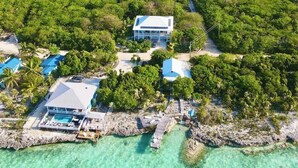 Vista aerea di un resort con diversi edifici, acque turchesi cristalline e vegetazione rigogliosa.