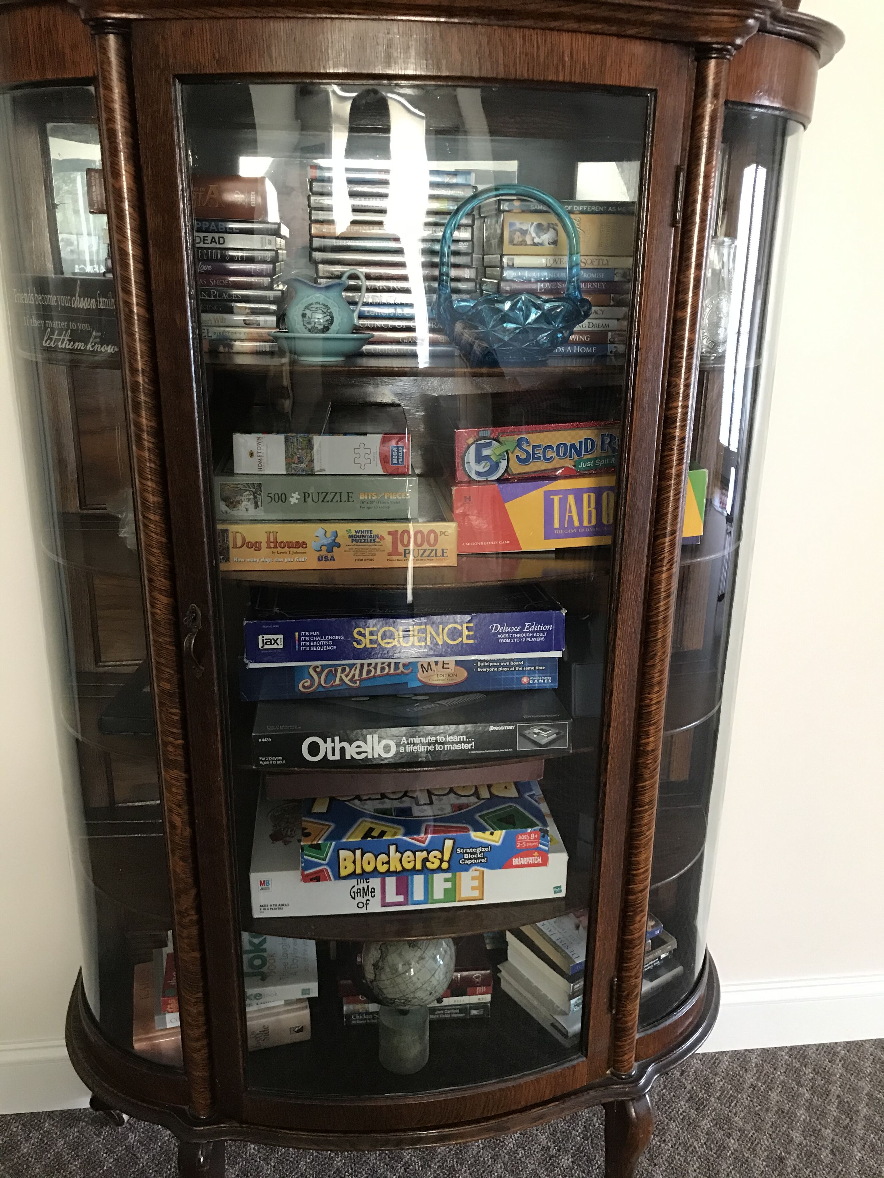 A wooden display case containing various board games and puzzles.