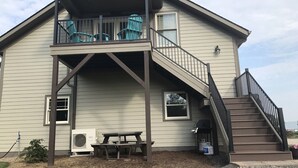Een twee verdiepingen tellend huis met een balkon, een trap en een picknicktafel.