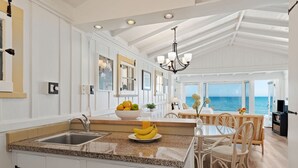 A spacious kitchen with a granite countertop, white cabinetry, and a view of the ocean. - Romantic Oceanfront Studio With Private Deck | Right On The Sand! (Santa Barbara)