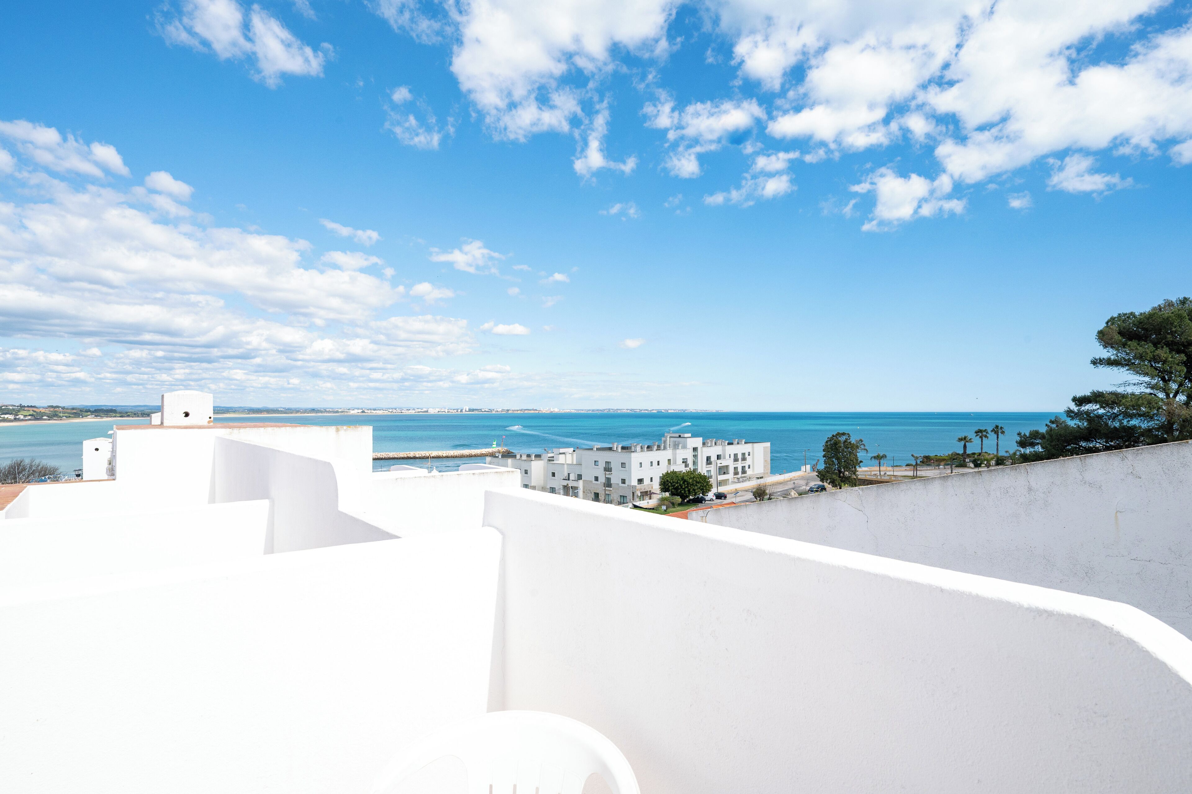 A coastal view with white buildings, a clear sky, and the sea in the background.