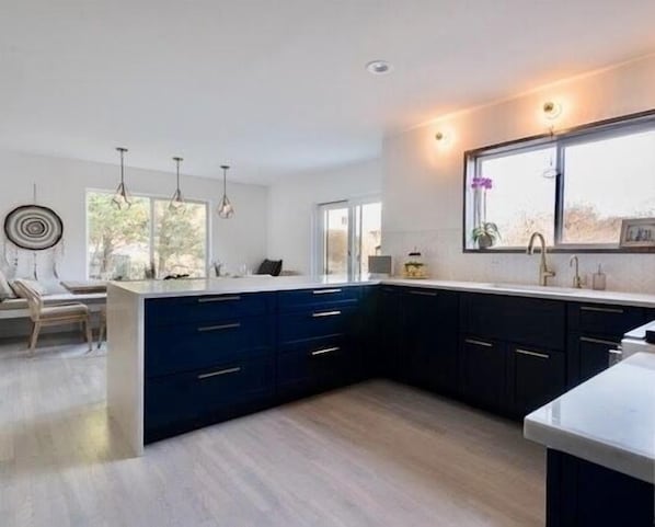 A modern kitchen with dark blue cabinets, a large island with a white countertop, and pendant lighting. - Ideal Montauk retreat with pool and hottub (Montauk)