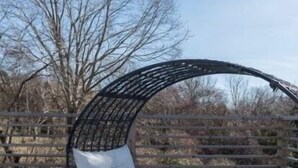 Un espace extérieur circulaire aménagé en coin salon, avec un banc rembourré et une structure en métal.