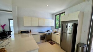 A modern kitchen with white cabinets, stainless steel appliances, and a large island.