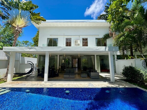 Une maison moderne à deux étages avec une piscine à l’avant.