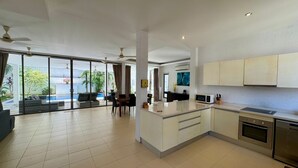 A spacious living area with a large sliding glass door leading to a balcony, a kitchen with modern appliances, and a dining area with a table and chairs.