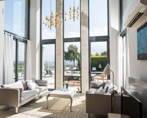 Relax in this spacious living room with a central coffee table and two sofas, offering a view of the pool and outdoor seating area.