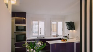 A modern kitchen with a central island, built-in oven, and a dining area with a table and chairs.