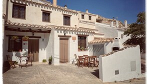 Un edificio tradizionale con un cortile interno, che presenta una piccola area salotto esterna con mobili in legno.
