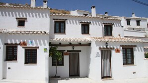 Un edificio bianco con molte finestre e porte, alcune con persiane, e un tetto in tegole.