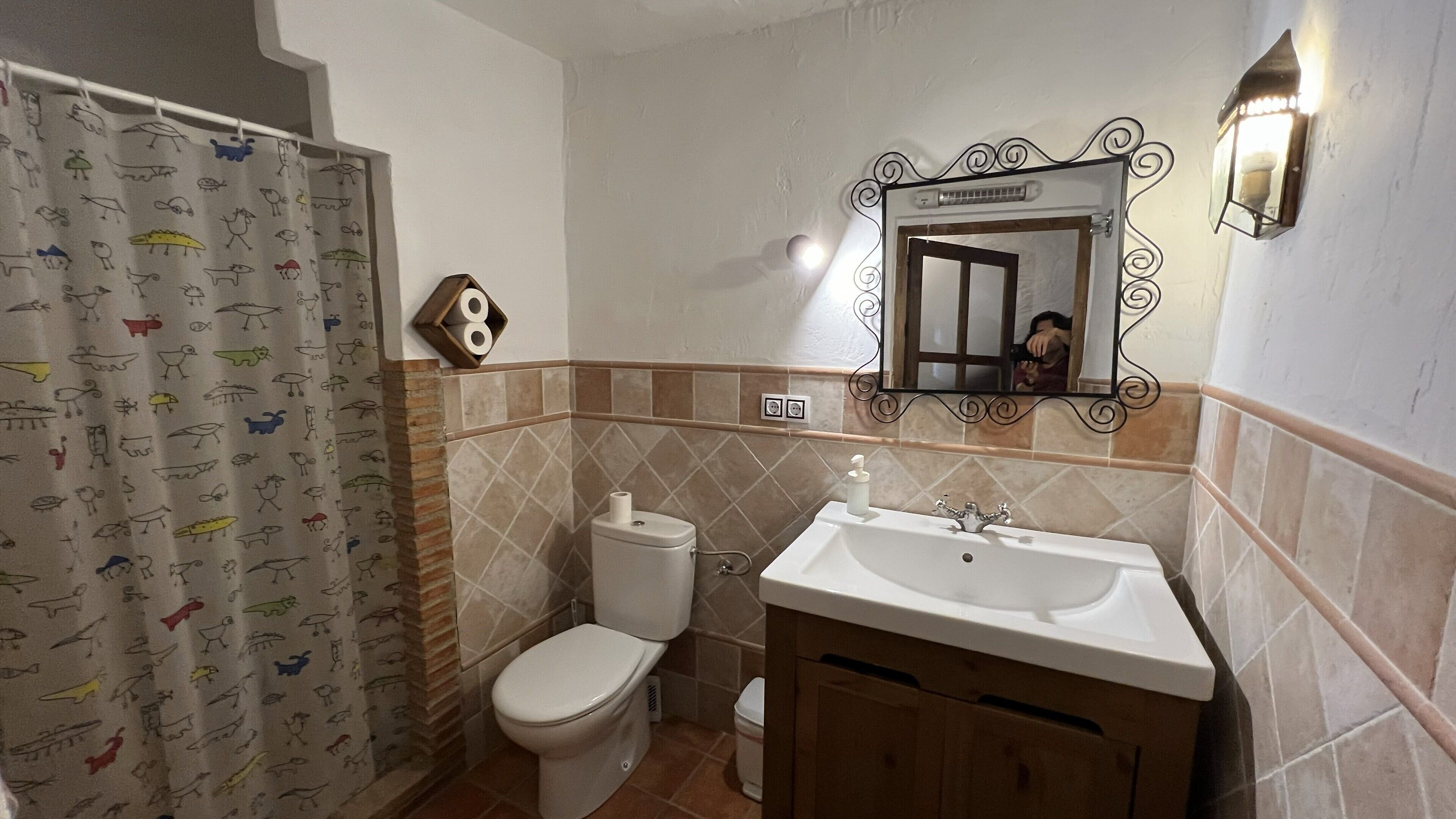 Un baño con inodoro, lavamanos y cortina de ducha.