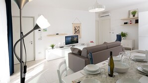 Een moderne woonkamer met een bank, televisie en een eethoek.